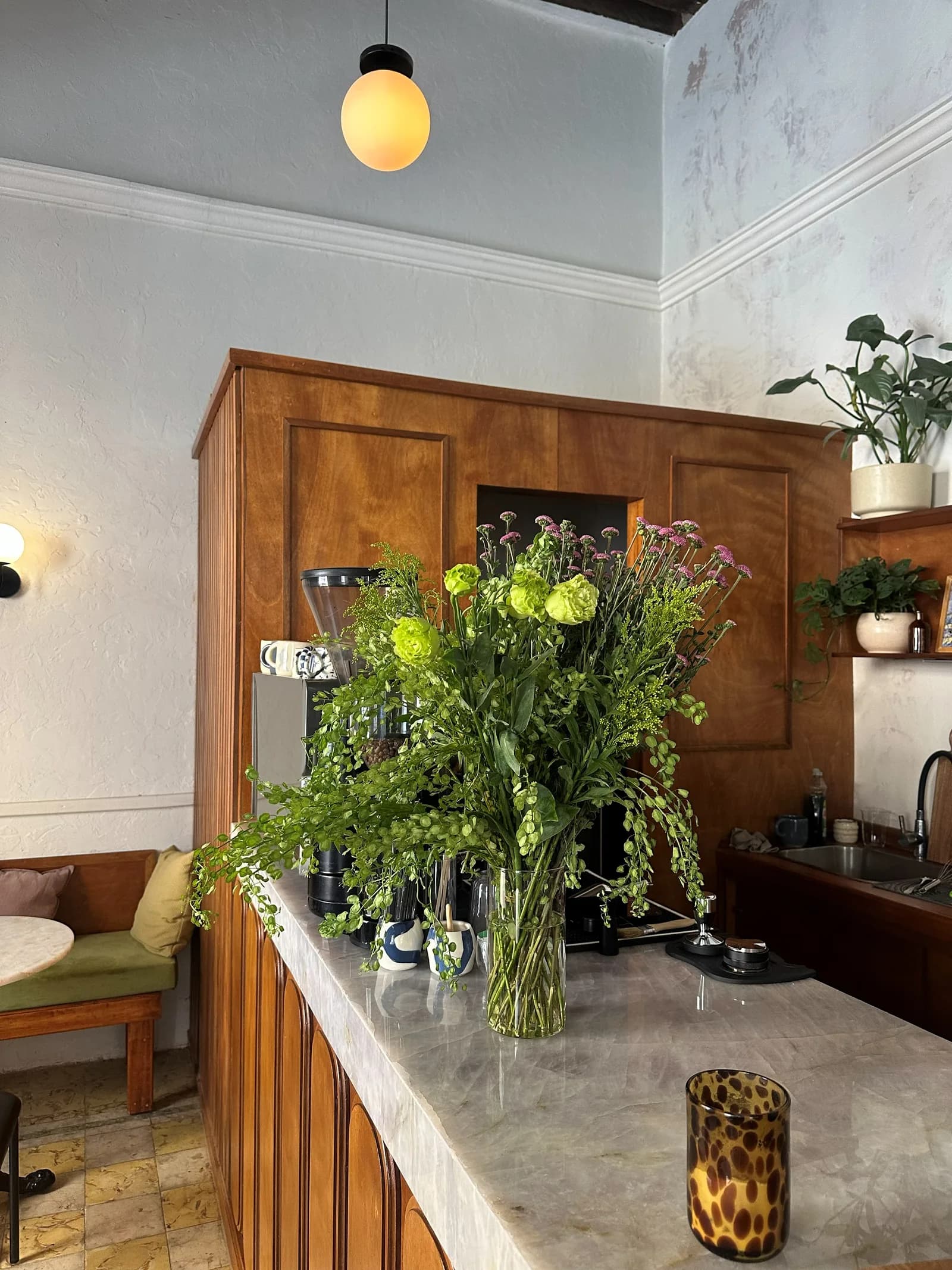 Interior del café: barra de madera con un arreglo de flores frescas.